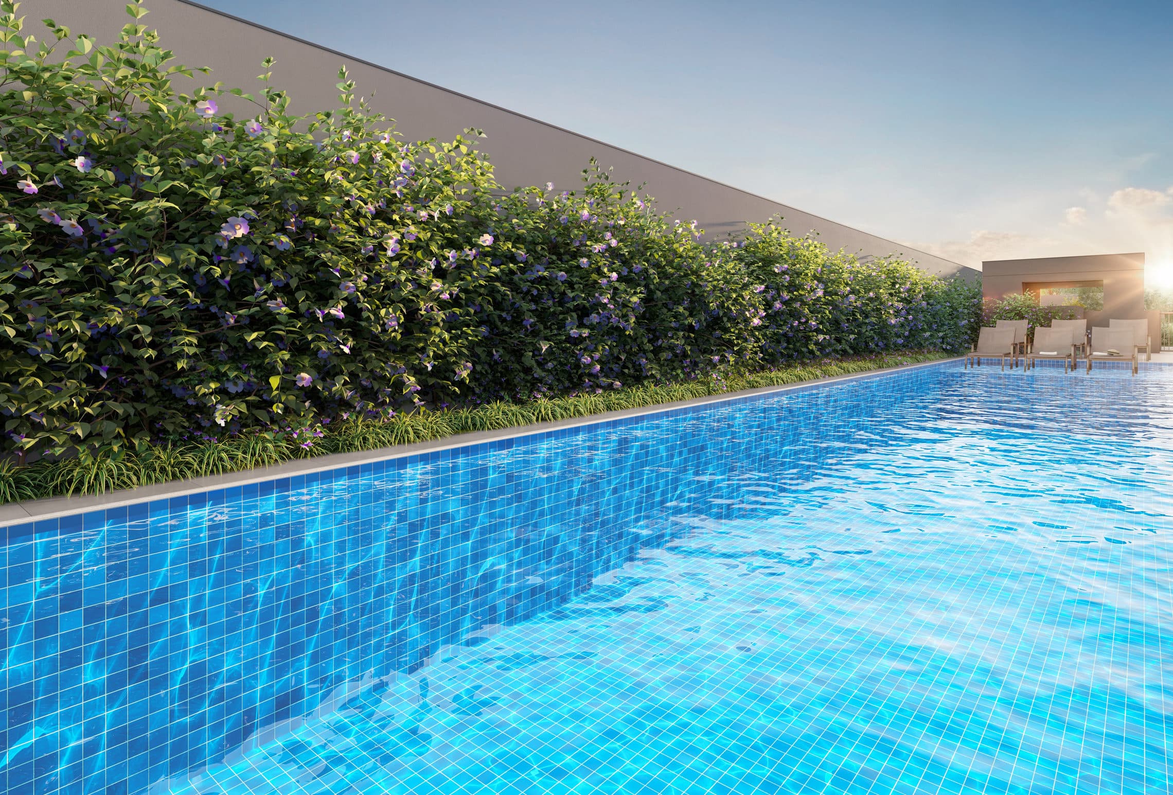 Piscina com borda revestida em azulejo azul, cercada por arbustos com flores e espreguiçadeiras ao fundo.