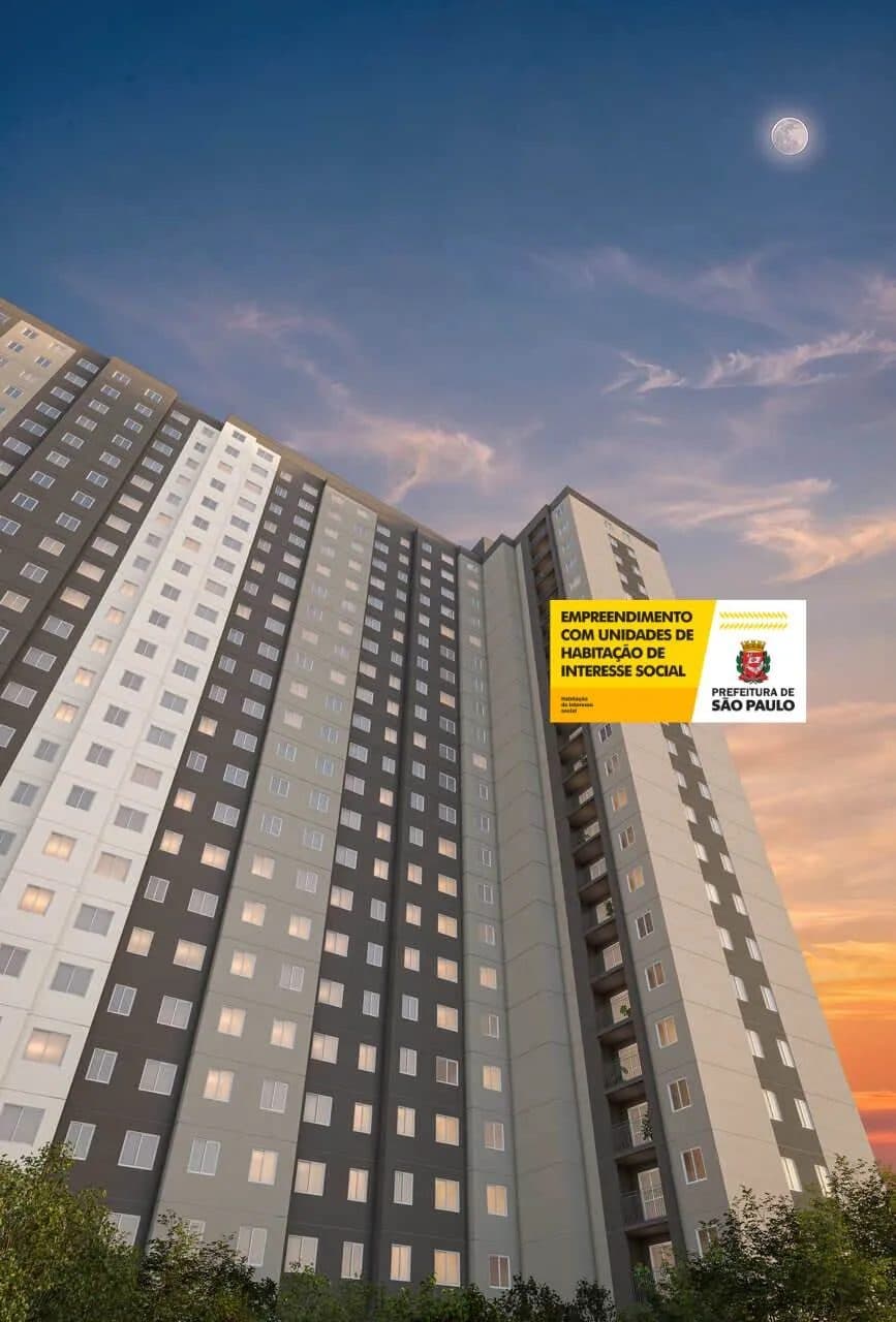 Fachada externa do edificio residencial com iluminacao noturna e ceu crepuscular.